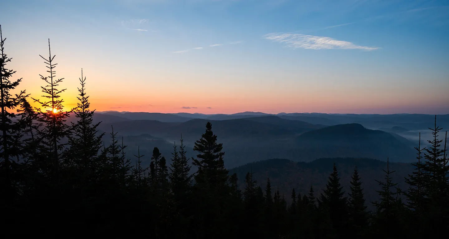 A scenery with mountains and trees at sunset (Photo)