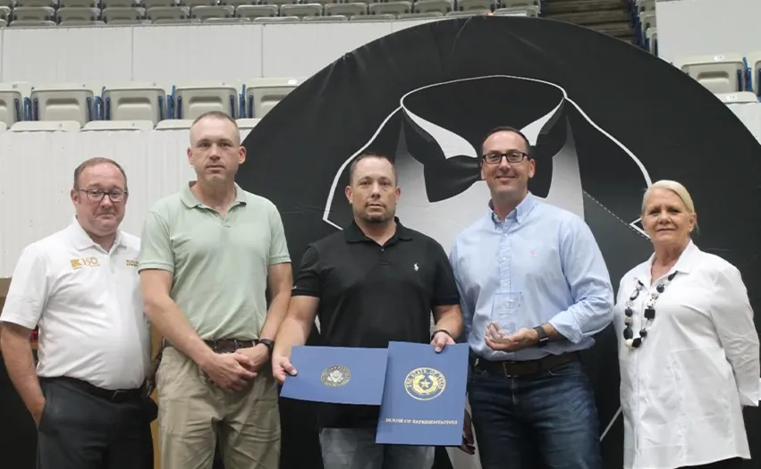 A group of five people. The one in the middle is holding the award. (Photo)